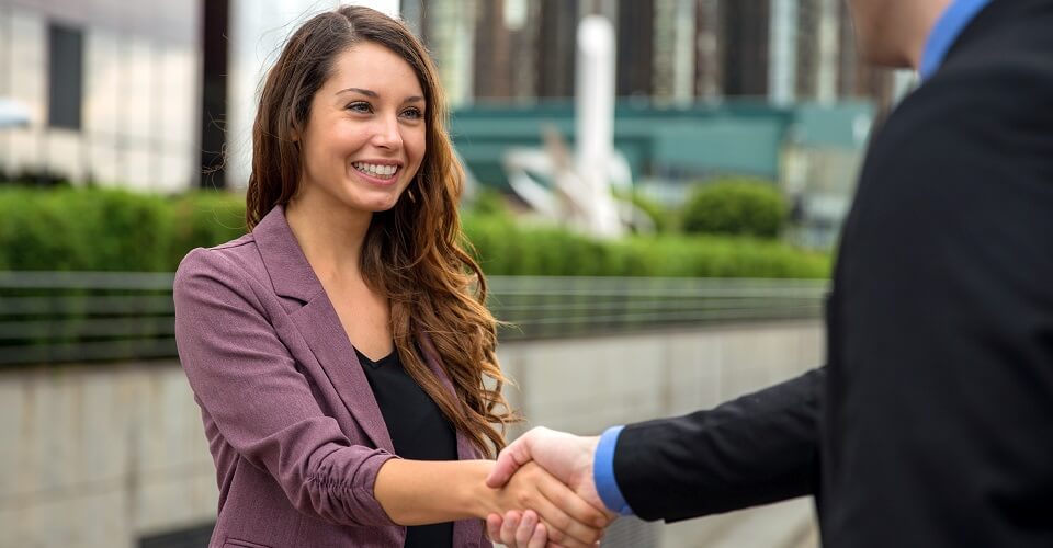 A smiling woman shakes hands with a man