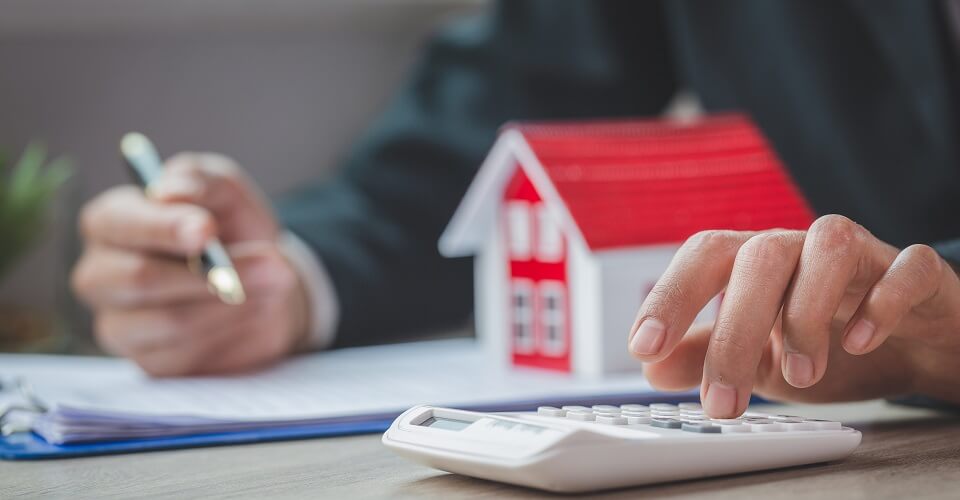 A model of a house with a white calculator next to it