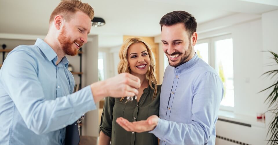 Real estate agent handing over the key to the happy couple